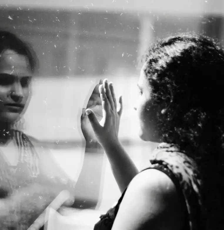 Mulher observa seu reflexo em uma janela.