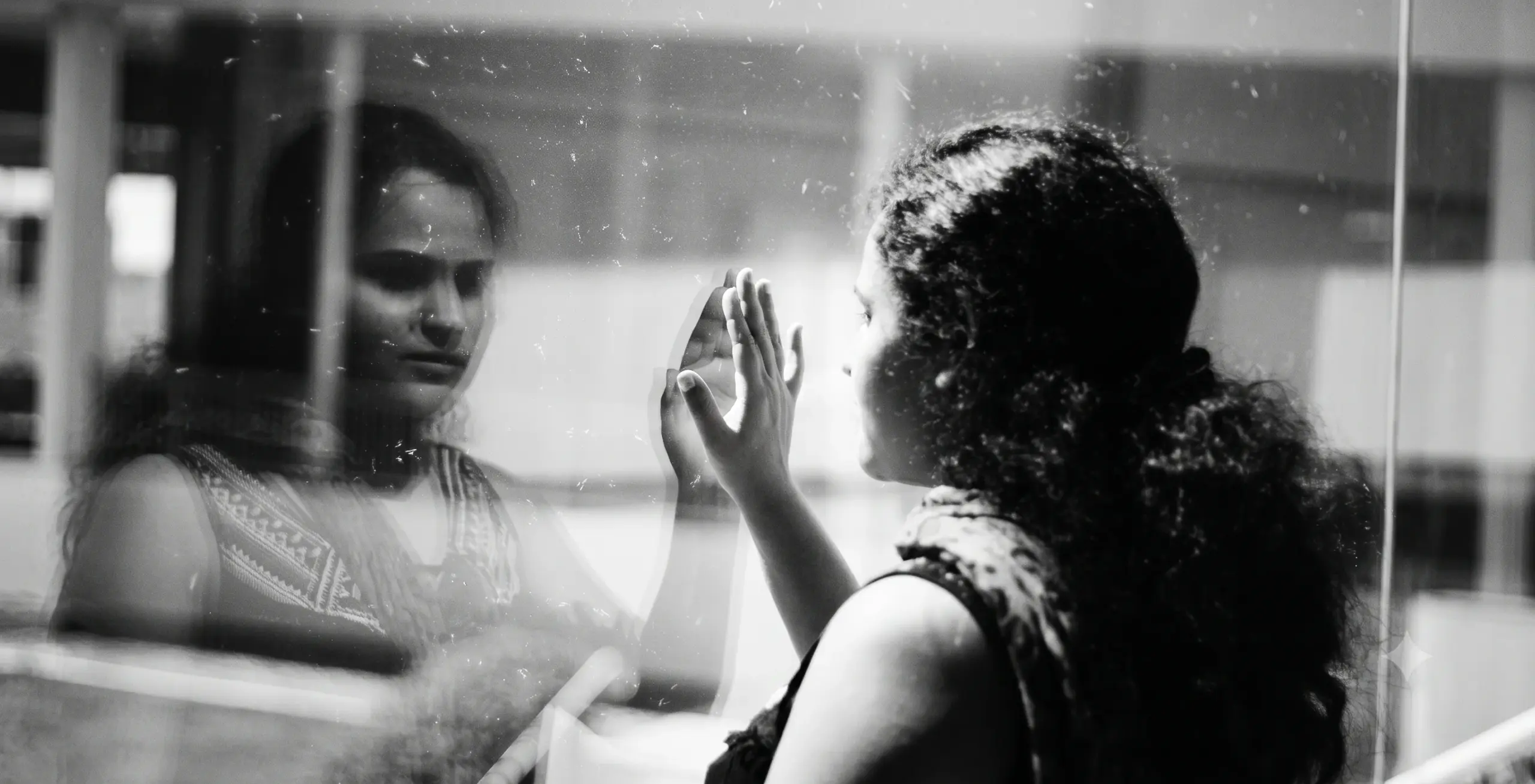 Mulher observa seu reflexo em uma janela.