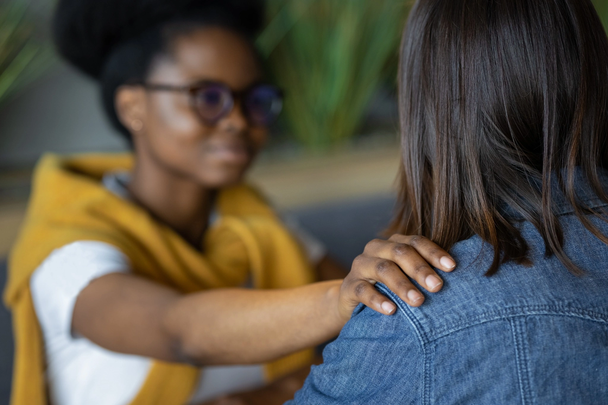 Duas mulheres de frente uma para a outra: uma consola a outra, com a mão apoiada no ombro.